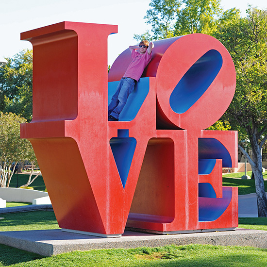 Carter sitting on Robert Indiana's LOVE Sculpture in Scottsdale Arizona, photo by Tom Grotta